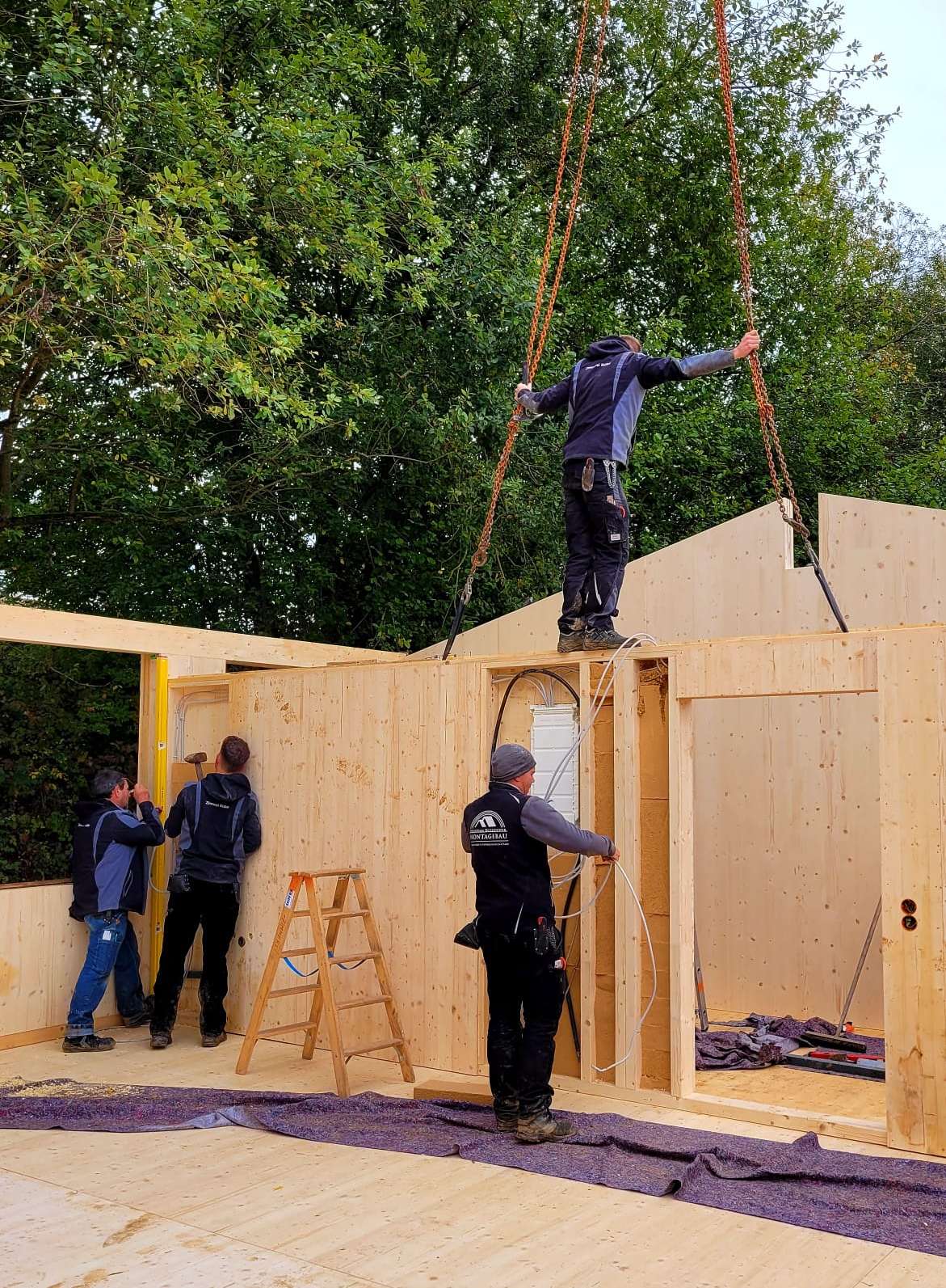 4 Männer beim Aufbau eines Holzhauses